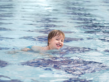 Toddler floats in paddling pool. teaching children to swim from early childhood. 