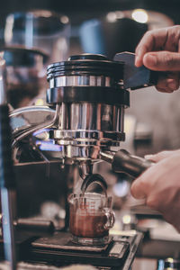 Cropped image of hand holding coffee cup at cafe