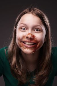 Portrait of smiling young woman against black background