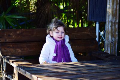 Girl looking away while standing amidst boardwalk