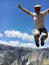 Man jumping over mountain against sky