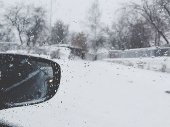 Close-up of waterdrops on glass against snowed landscape