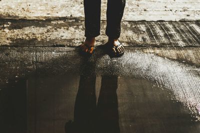 Low section of person standing by puddle on road