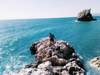 High angle view of man walking on rock in sea against sky