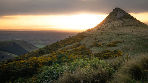 Sun setting down behind an unusually shaped mountain,sunset at port hills,christchurch, new zealand