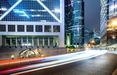 Light trails on road by buildings in city at night