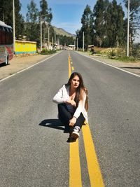 Full length of woman sitting on road in city