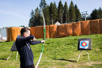 Man aiming bow while standing outdoor