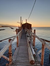 Pier over sea against sky during sunset