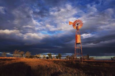 Low angle view of traditional windmill on field against sky