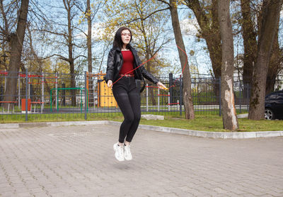 Full length portrait of woman on footpath in city