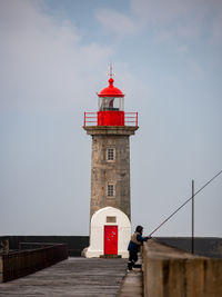 Lighthouse by sea against sky