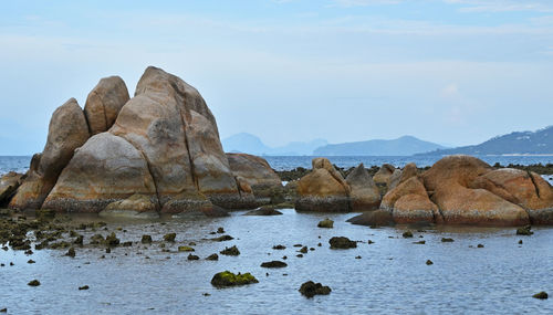 Scenic view of rocks in sea against cloudy sky