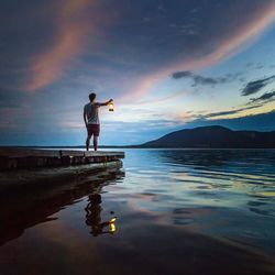 Man standing on beach against sky at sunset