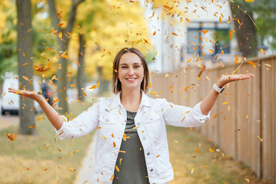 Portrait of smiling young woman standing by plants