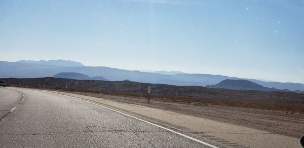 Empty road by mountains against sky