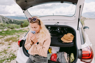 Young woman wearing sunglasses while sitting in car