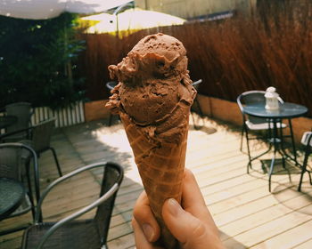 Cropped hand holding chocolate ice cream cone