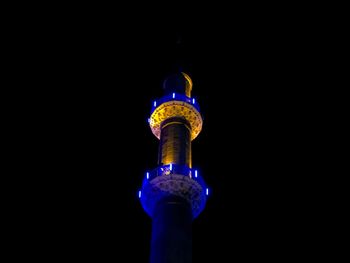 Low angle view of illuminated communications tower against sky at night