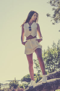 Portrait of young woman standing against clear sky