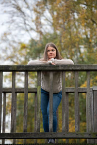 Portrait of young woman standing against railing