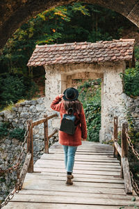 Rear view of woman on wooden footbridge, old castle, medieval.