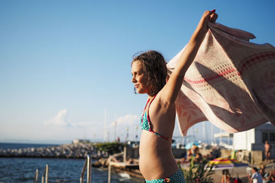 Side view of girl holding towel at beach