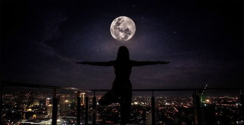 Moon in city against sky at night