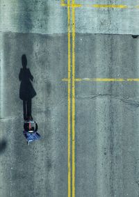 Directly above shot of man riding bicycle on road during sunny day