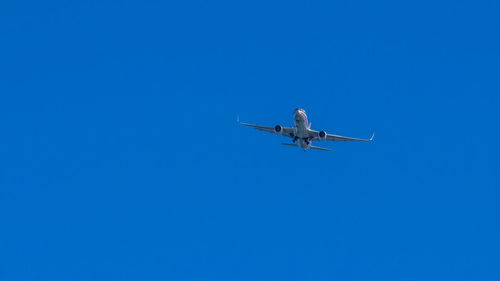 Low angle view of airplane against clear blue sky