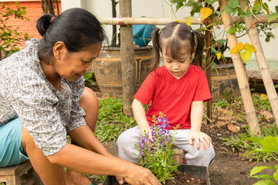 Rear view of mother and daughter by potted plants