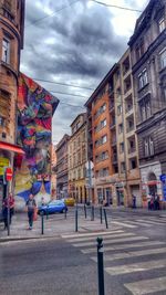 View of city street against cloudy sky