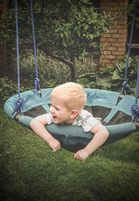 Boy playing on swing at playground