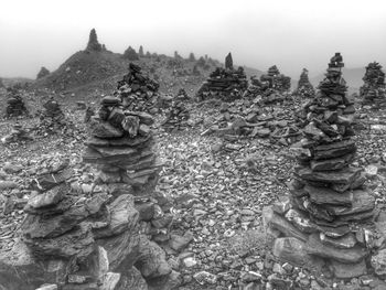 Stone stacks on field against sky