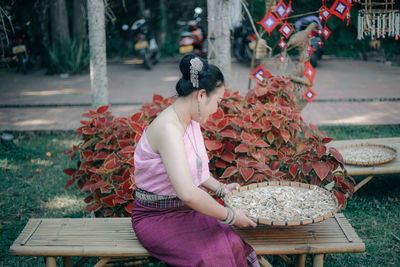 Side view of sitting on bench by plants