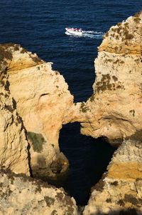 Boat in calm sea with rocks in foreground