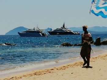 Rear view of woman walking on beach against clear sky