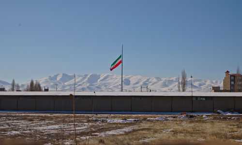 Flag on field against clear sky during winter