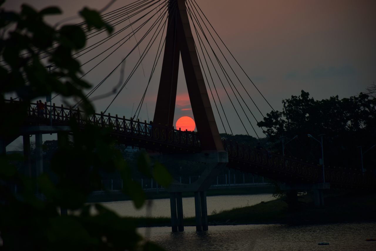 BRIDGE OVER SILHOUETTE TREES AGAINST SKY DURING SUNSET
