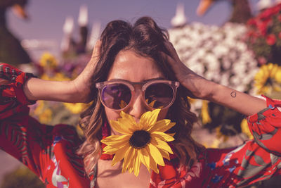 Portrait young woman holding flower in mouth