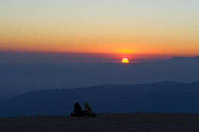 Silhouette people on mountain against sky during sunset