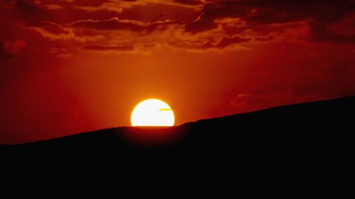 Scenic view of silhouette mountain against orange sky