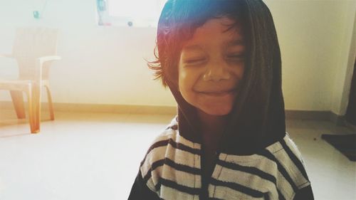 Close-up of smiling boy with eyes closed at home