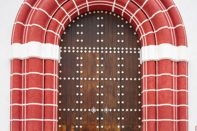 Arched wooden door with decorated white elements. red style gate frame