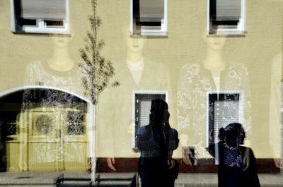 Rear view of people standing against window in building