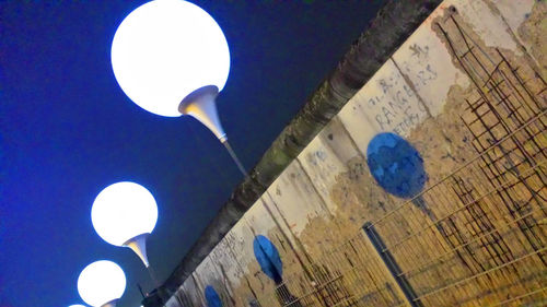 Low angle view of illuminated street light against blue sky