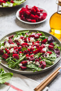 Arugula, beet and cheese salad with pomegranate and dressing on plate 