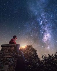 Low angle view of man sitting against sky at night