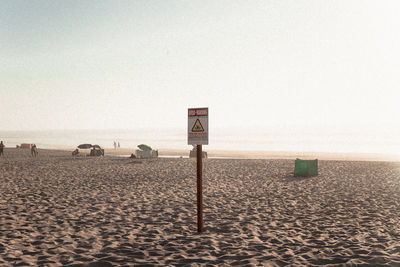 Wooden post on beach against clear sky