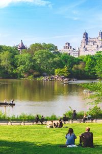 Group of people in park by lake against sky